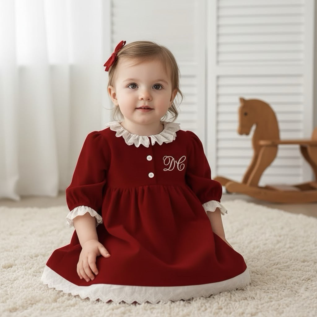 Girl sat on the floor wearing red dress with her initials on it